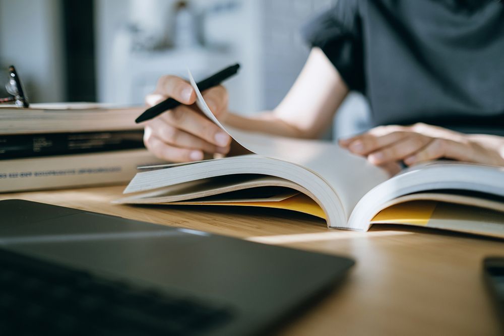 A person is writing in a notebook while sitting at a table.