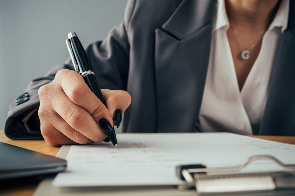 A woman is writing on a piece of paper with a pen.