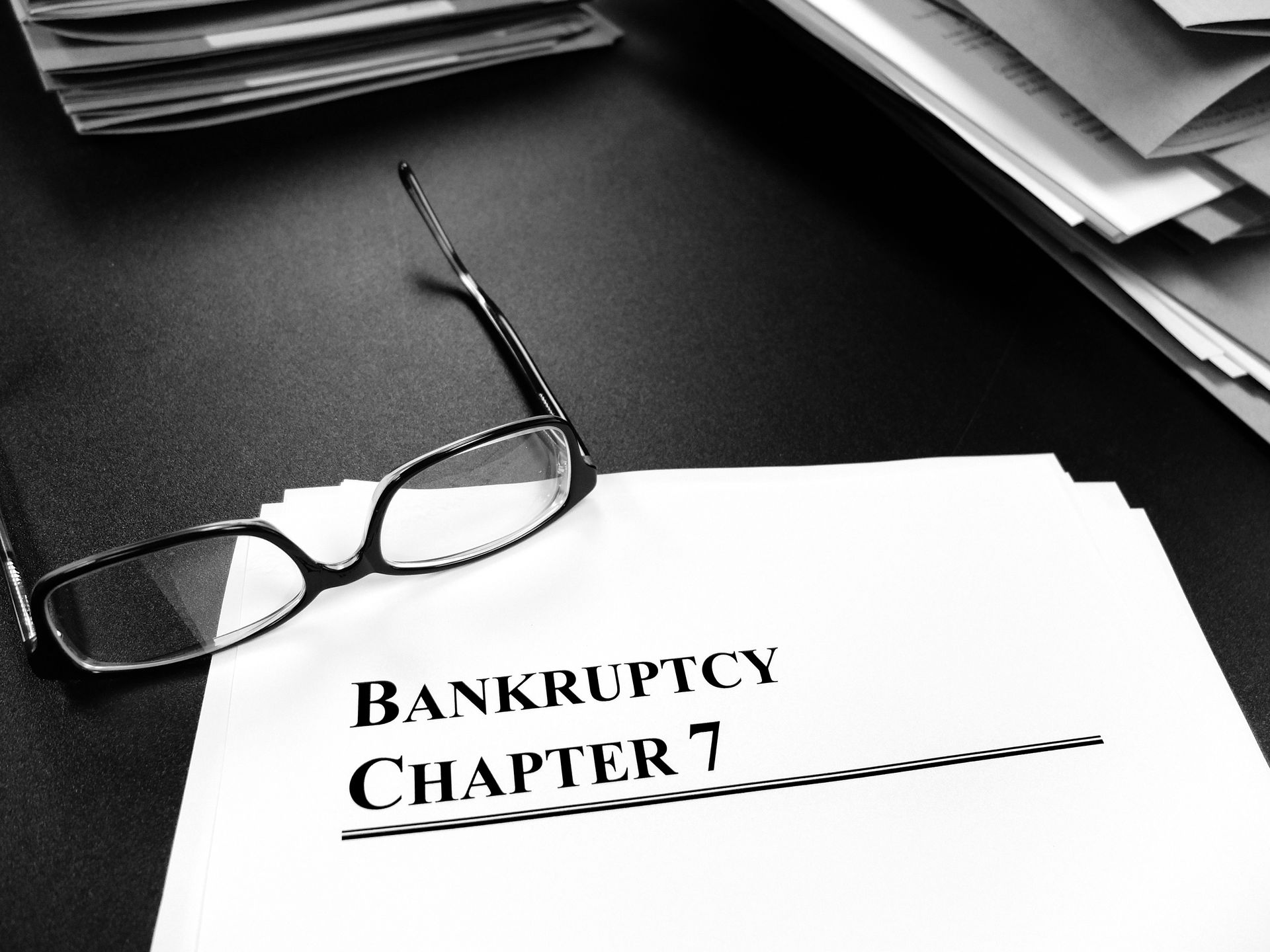 Document titled ‘Bankruptcy Chapter 7’ with eyeglasses on a desk. Document titled ‘Bankruptcy Chapter 7’ with eyeglasses on a desk.