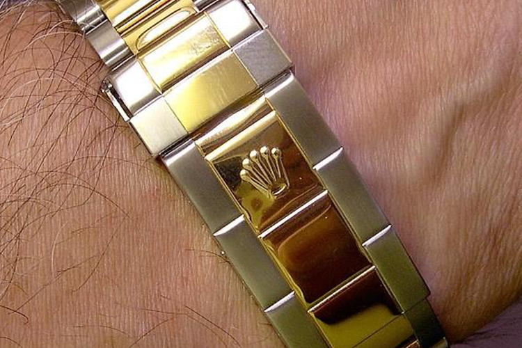 A man wearing a gold and silver rolex watch on his wrist