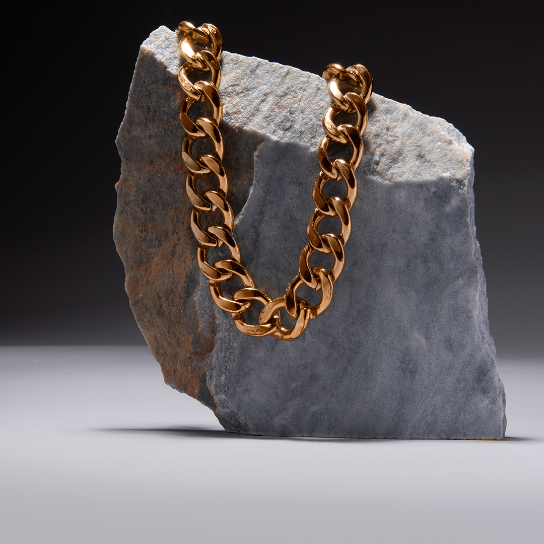 A gold chain is sitting on top of a rock