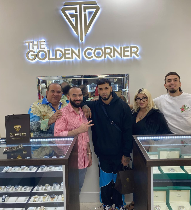 A group of people are posing for a picture in front of a sign that says the golden corner
