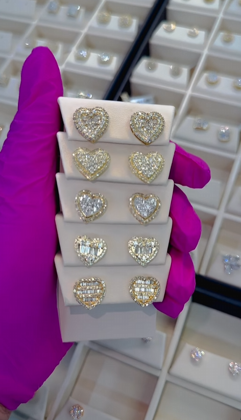 A person wearing a pink glove is holding a stack of heart shaped earrings.