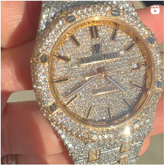 A person is holding a watch that is covered in diamonds