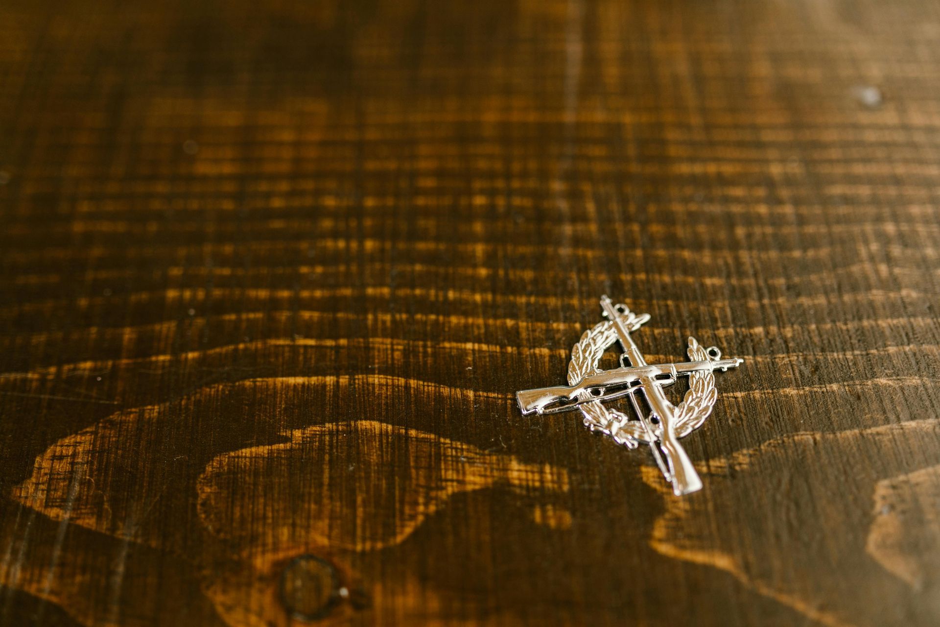 Une croix en argent est posée sur une table en bois.