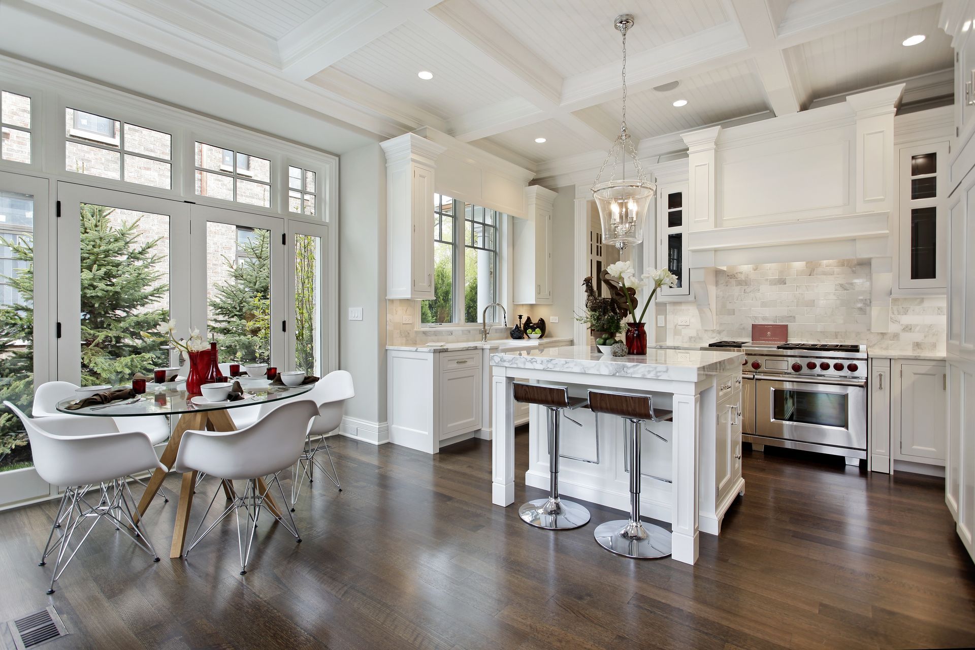 Bright modern kitchen and dining area with white cabinetry, island seating, and large windows
