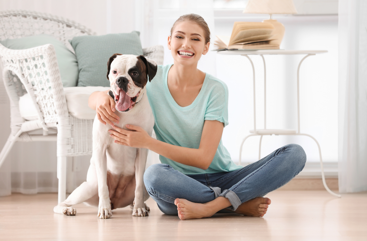 A woman is sitting on the floor with her dog.