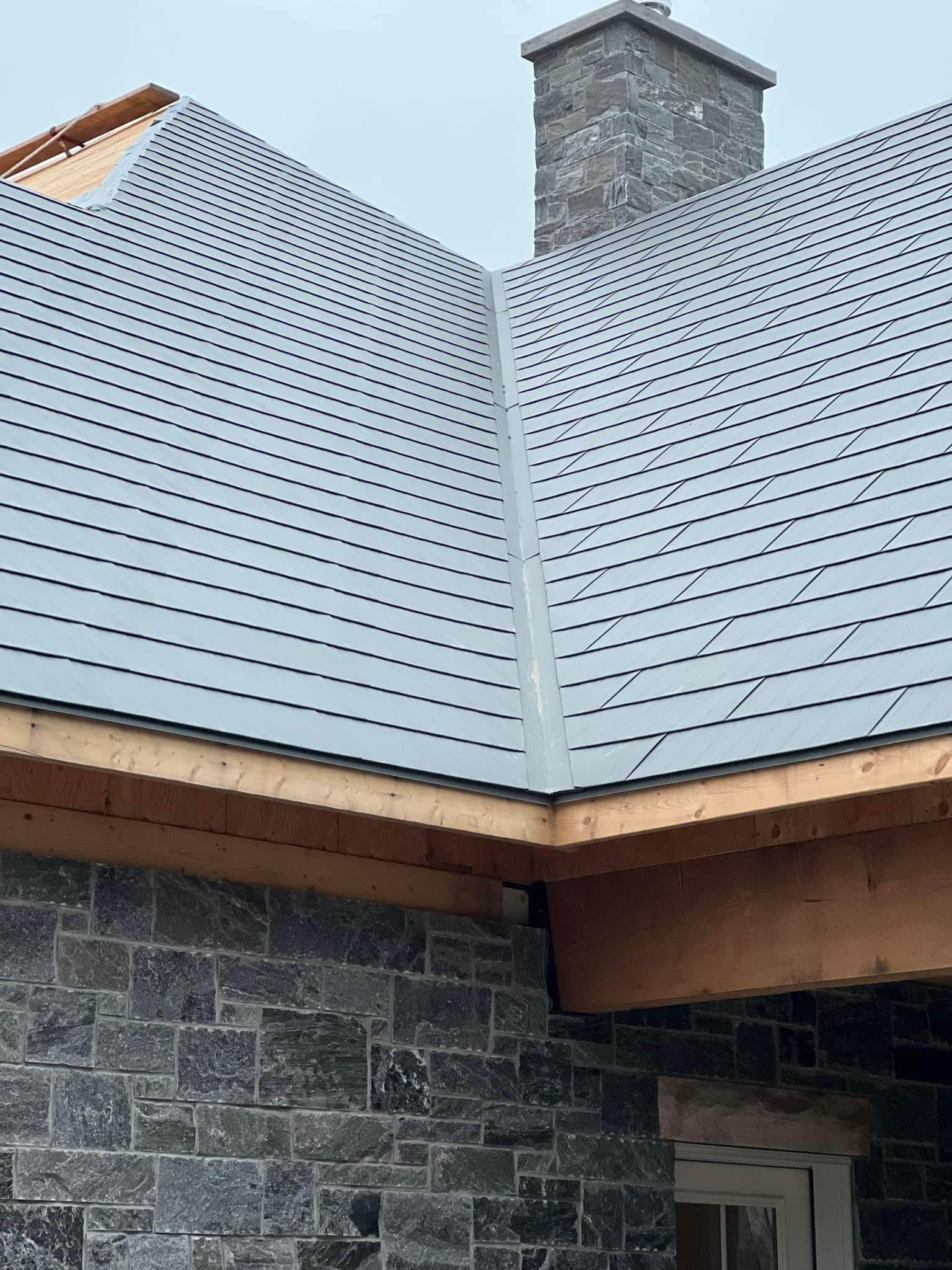 A close up of a roof with a chimney on a brick building.