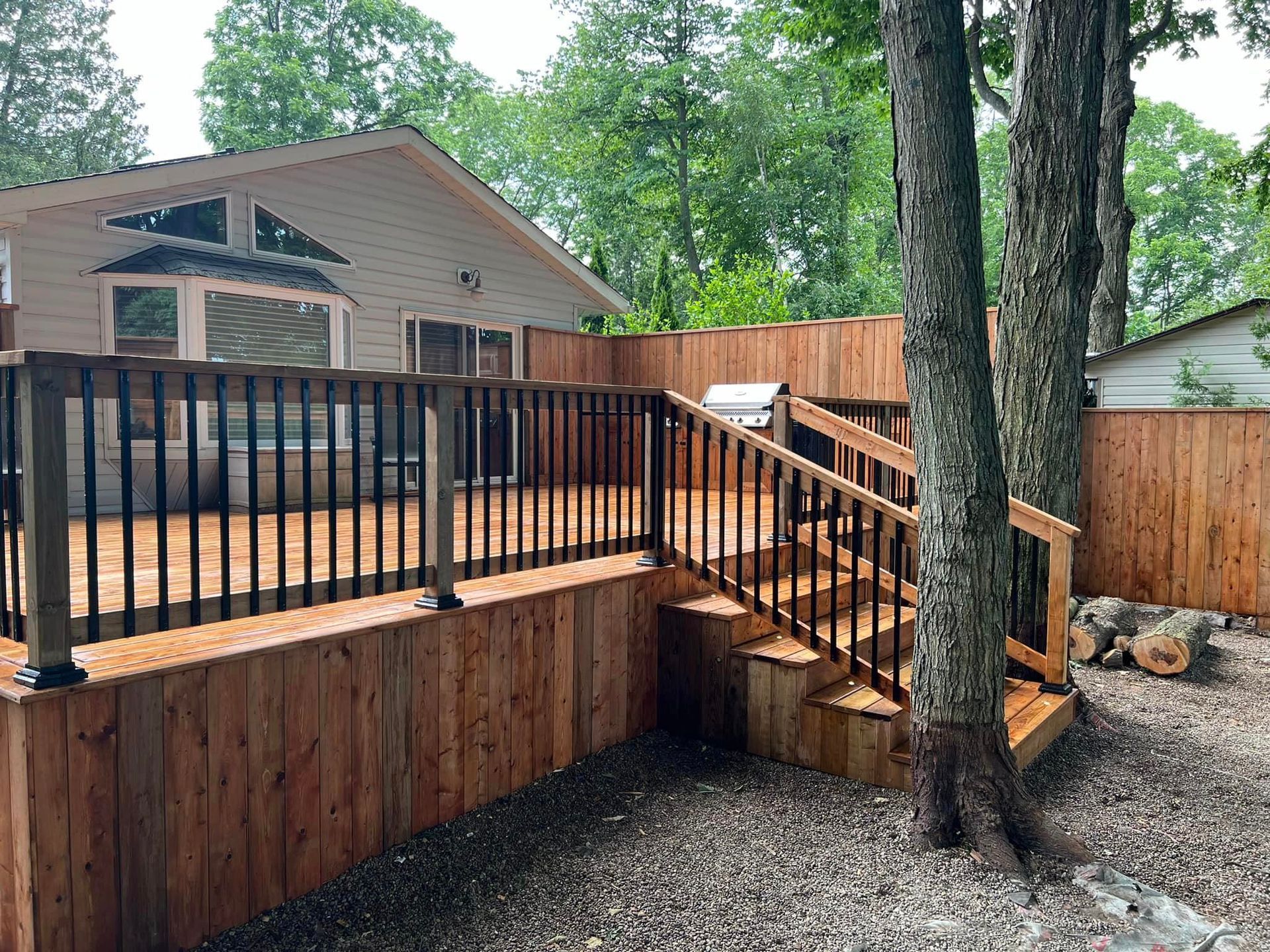 A wooden deck with stairs leading up to it is surrounded by a wooden fence.