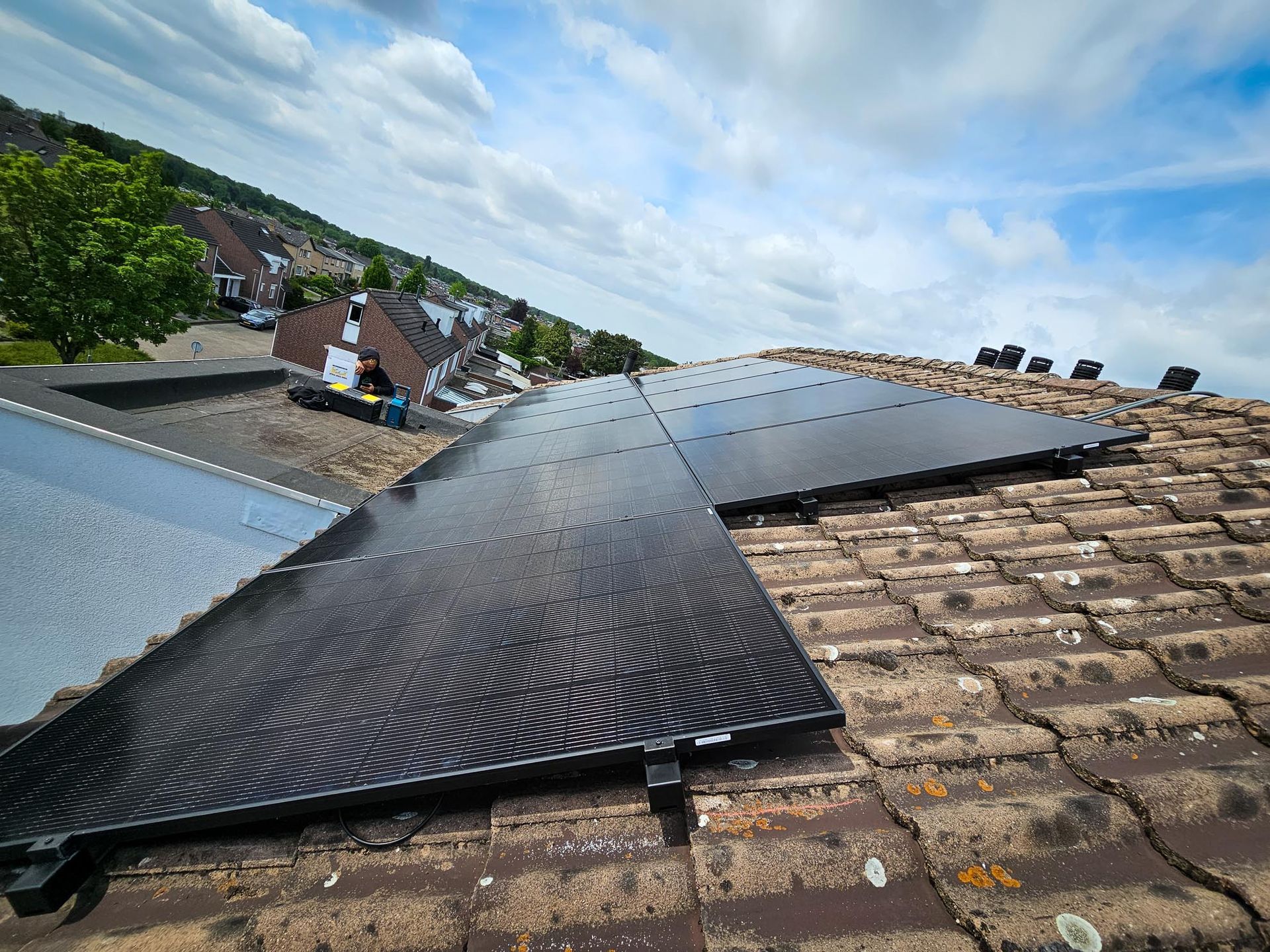 Een rij zonnepanelen staat op een bakstenen dak.