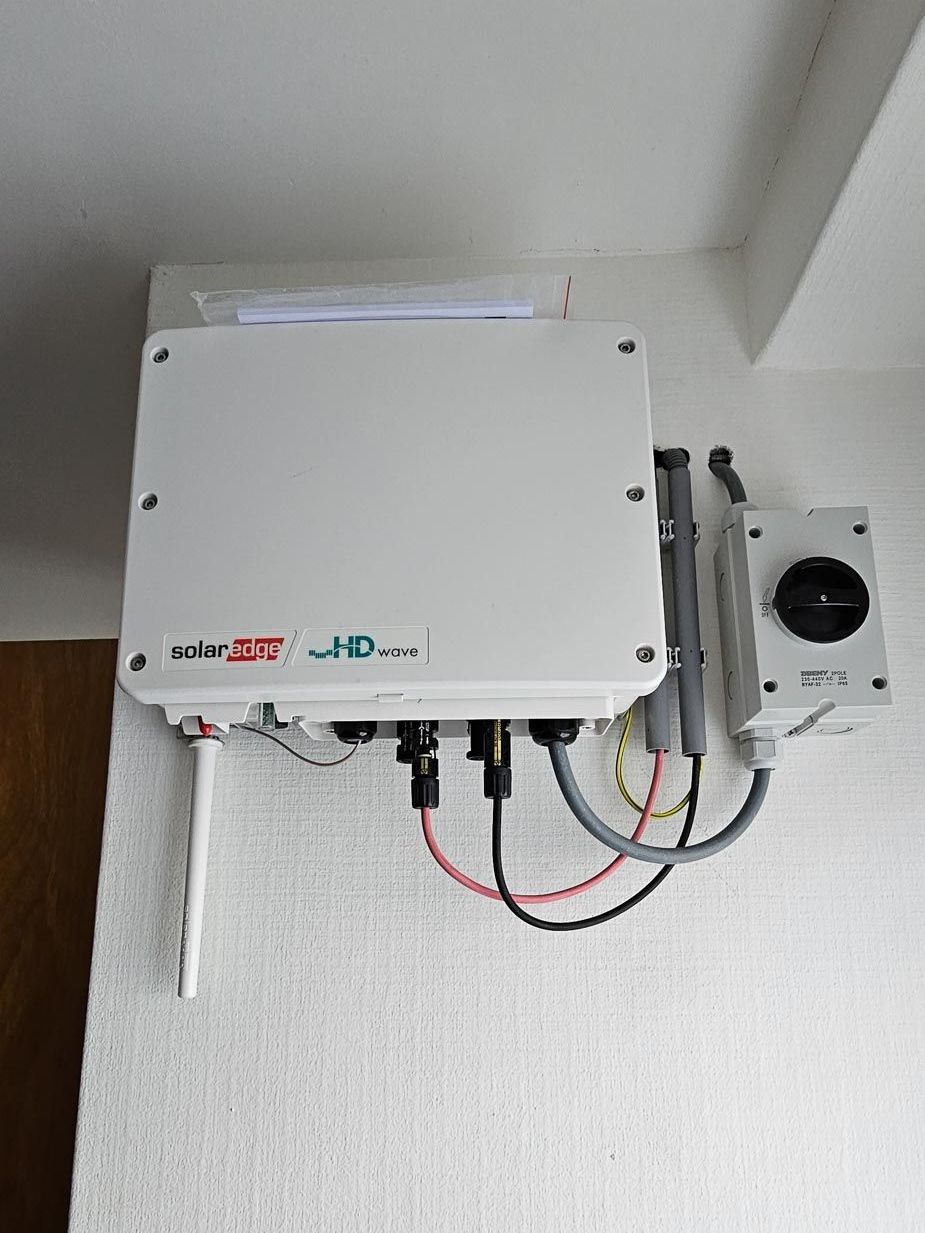 Een witte doos met draden die eruit komen hangt aan de muur.