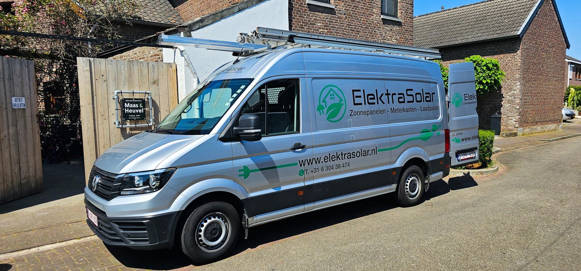 Een zilveren busje staat geparkeerd voor een bakstenen gebouw.