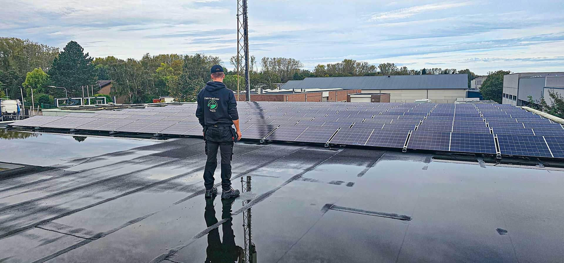 Een man staat op een dak met veel zonnepanelen.