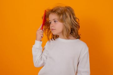 a little girl holding a red brush in her hand