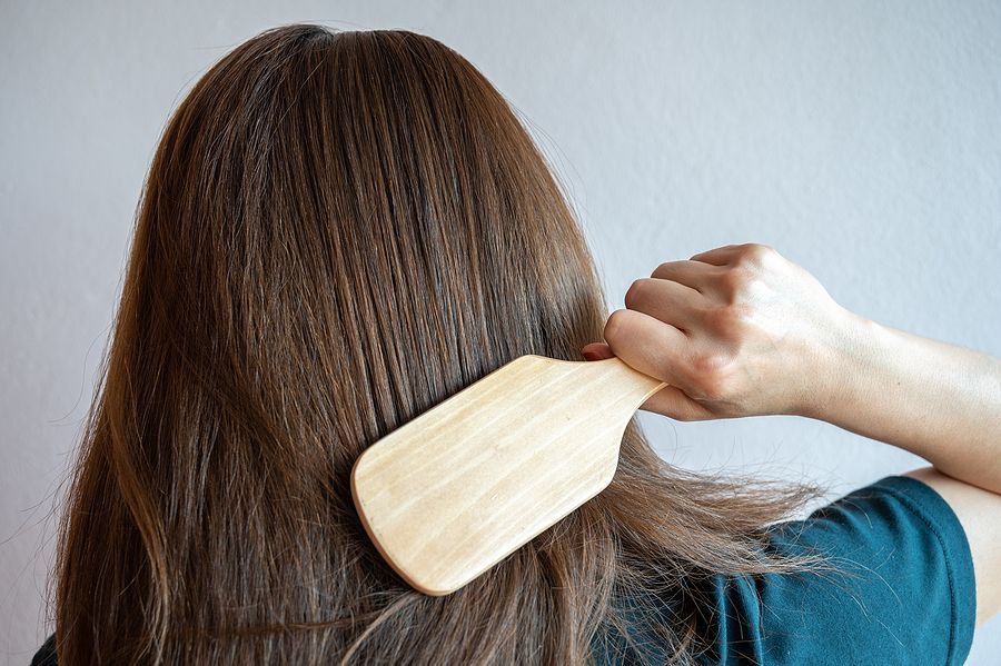 a woman brushing her hair with a wooden comb