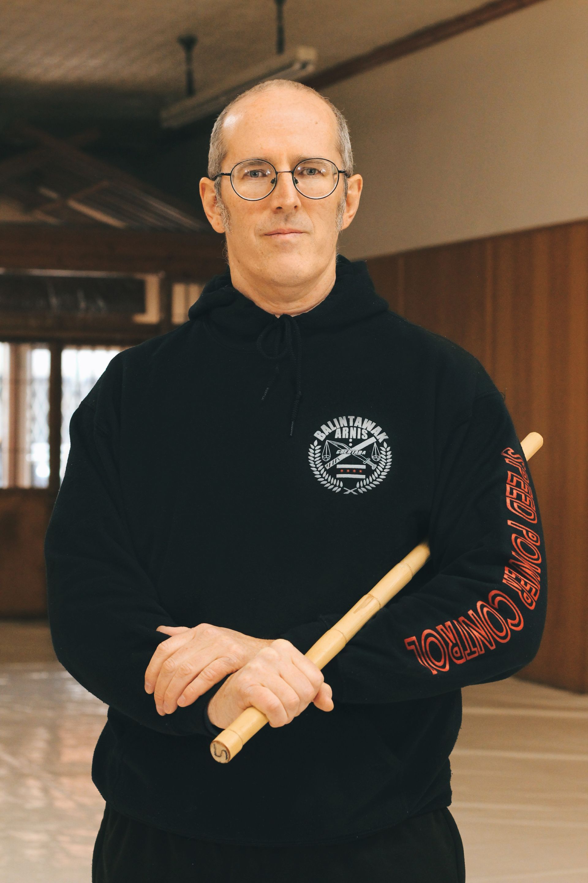 A man in a black sweatshirt is holding a wooden stick.