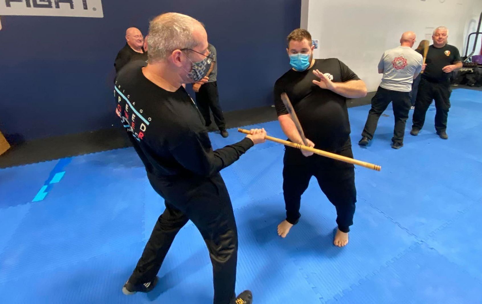 A group of men are practicing martial arts on a blue mat.