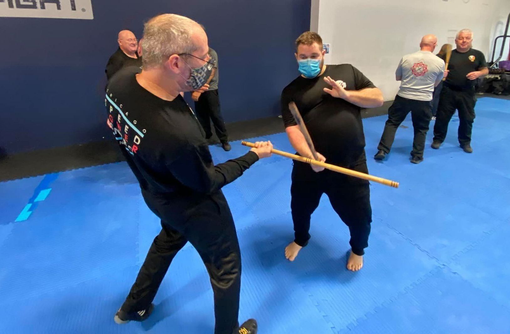 A group of men are practicing martial arts on a blue mat.