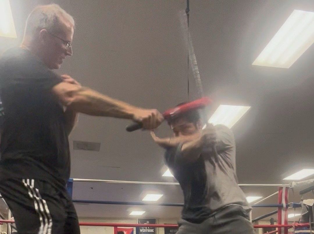 Two men are fighting in a boxing ring and one of them is wearing adidas shorts