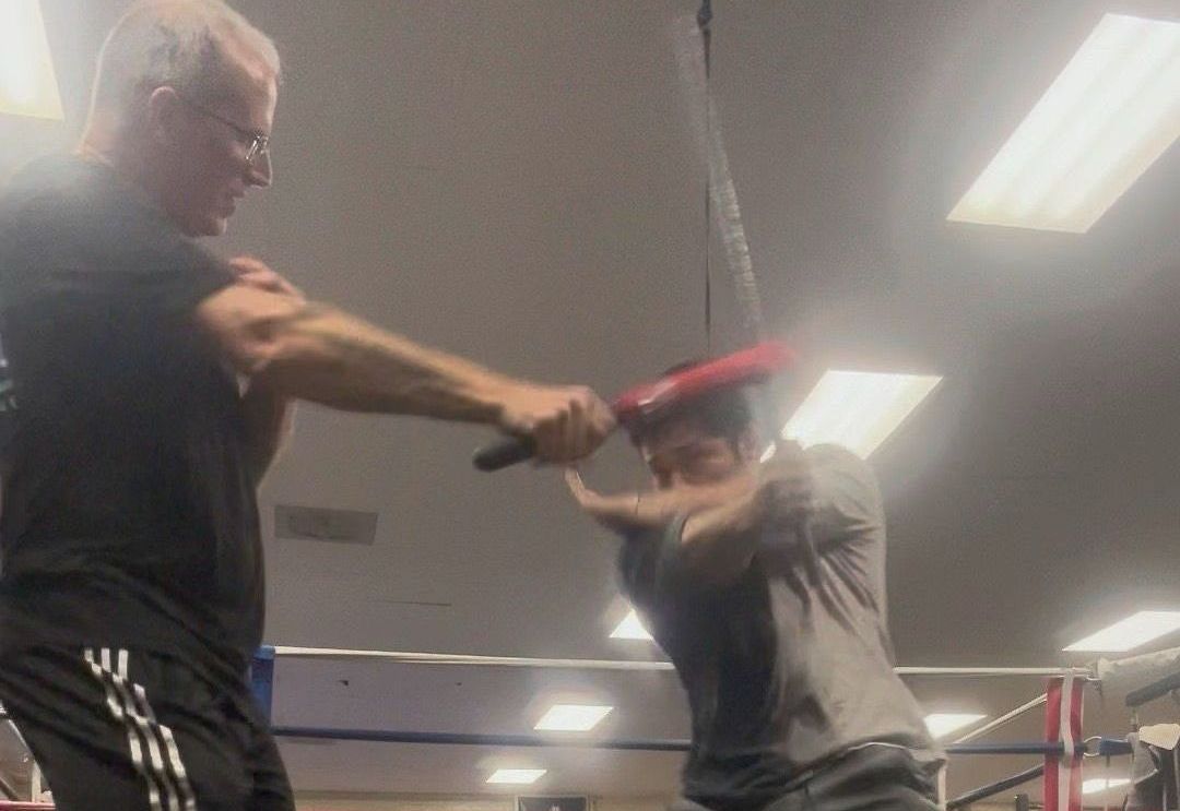 Two men are practicing martial arts in a gym.