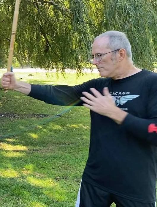 A man in a chicago shirt is holding a bamboo stick