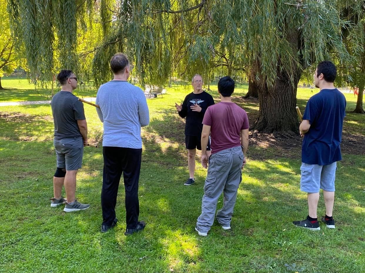 A group of men are standing in a park talking to each other.