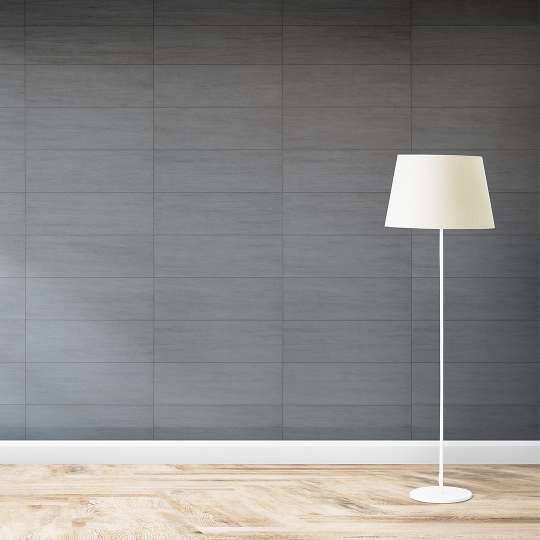 A white floor lamp is sitting in front of a gray wall.