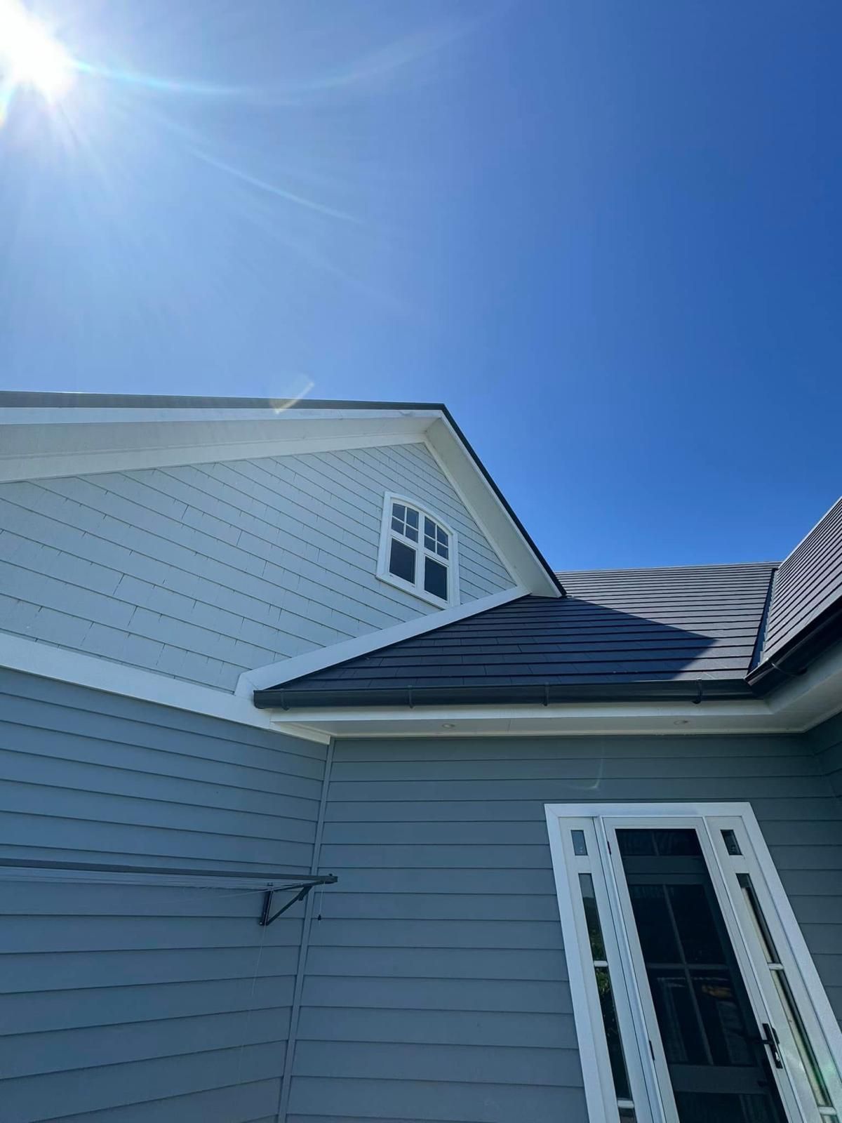 A house with a solar panel on the roof and a blue sky in the background.