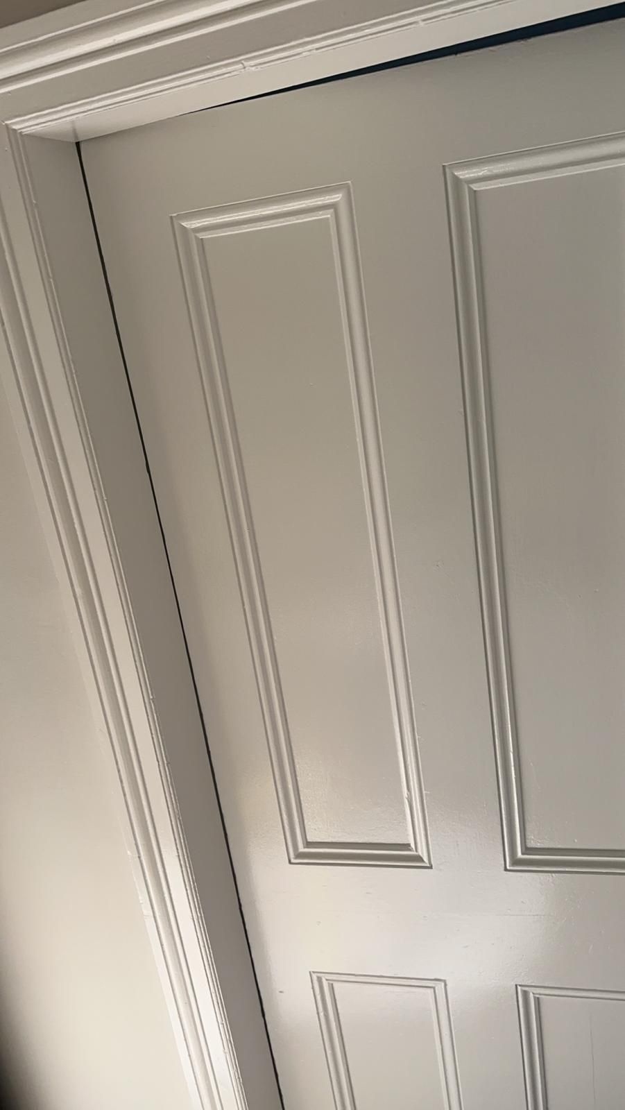 A close up of a white door with a white trim.