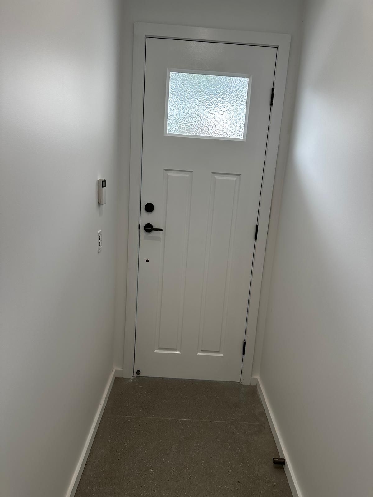 A hallway with a white door and a small window