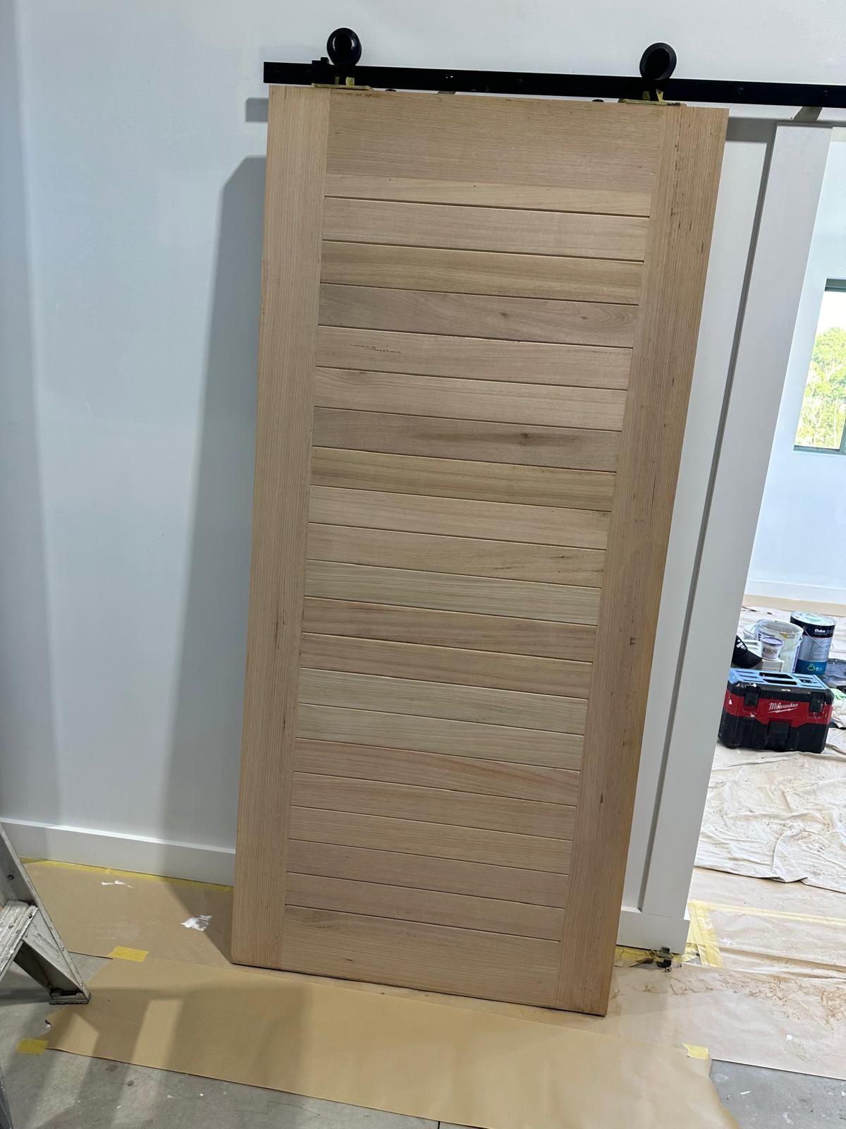 A wooden sliding barn door is sitting on the floor in a room.