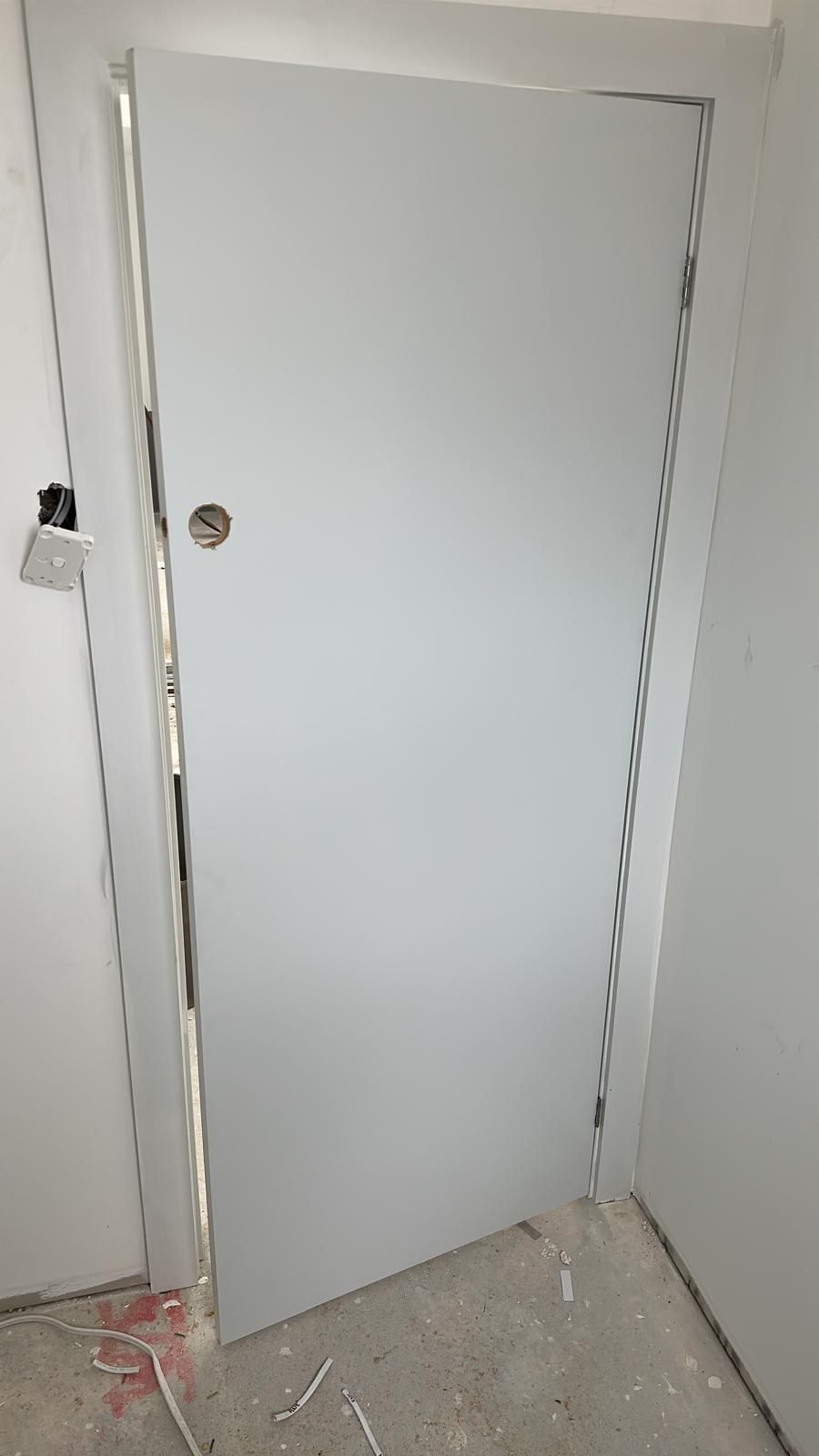 A white door is sitting in a room next to a wall.