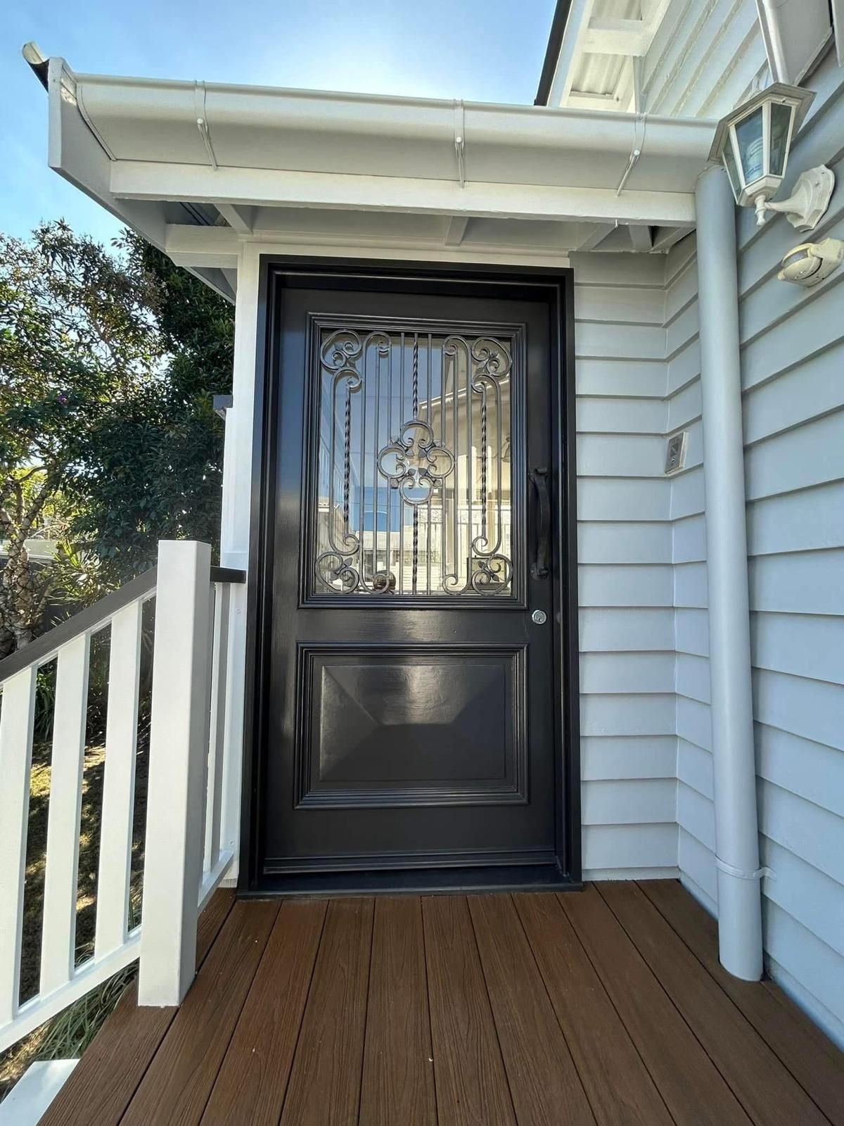 A black door is sitting on a wooden deck next to a white house.