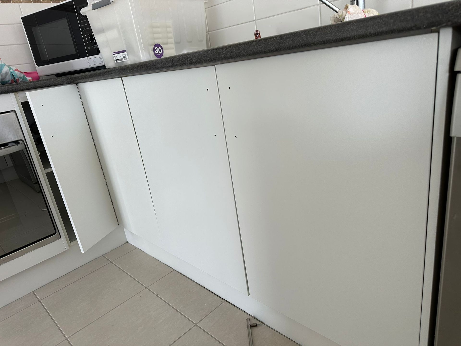A kitchen with white cabinets and a black counter top