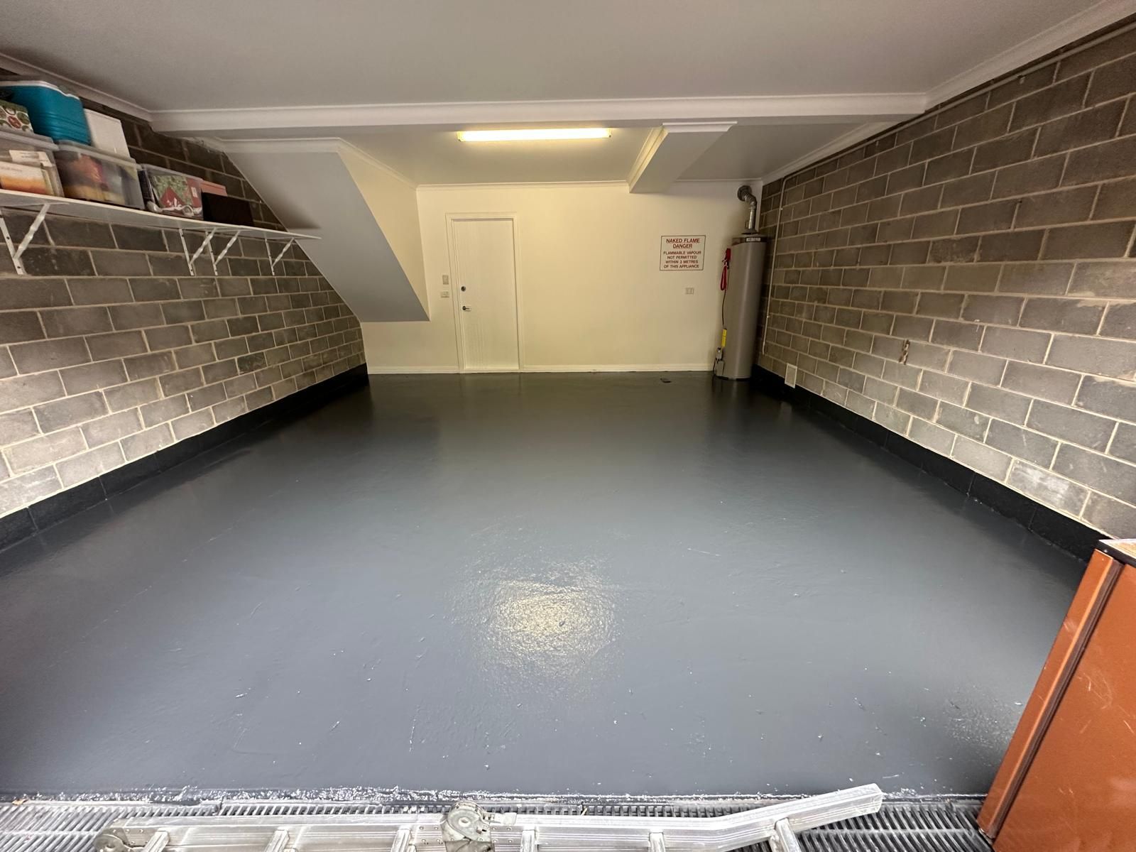 A garage with a brick wall and a gray floor.