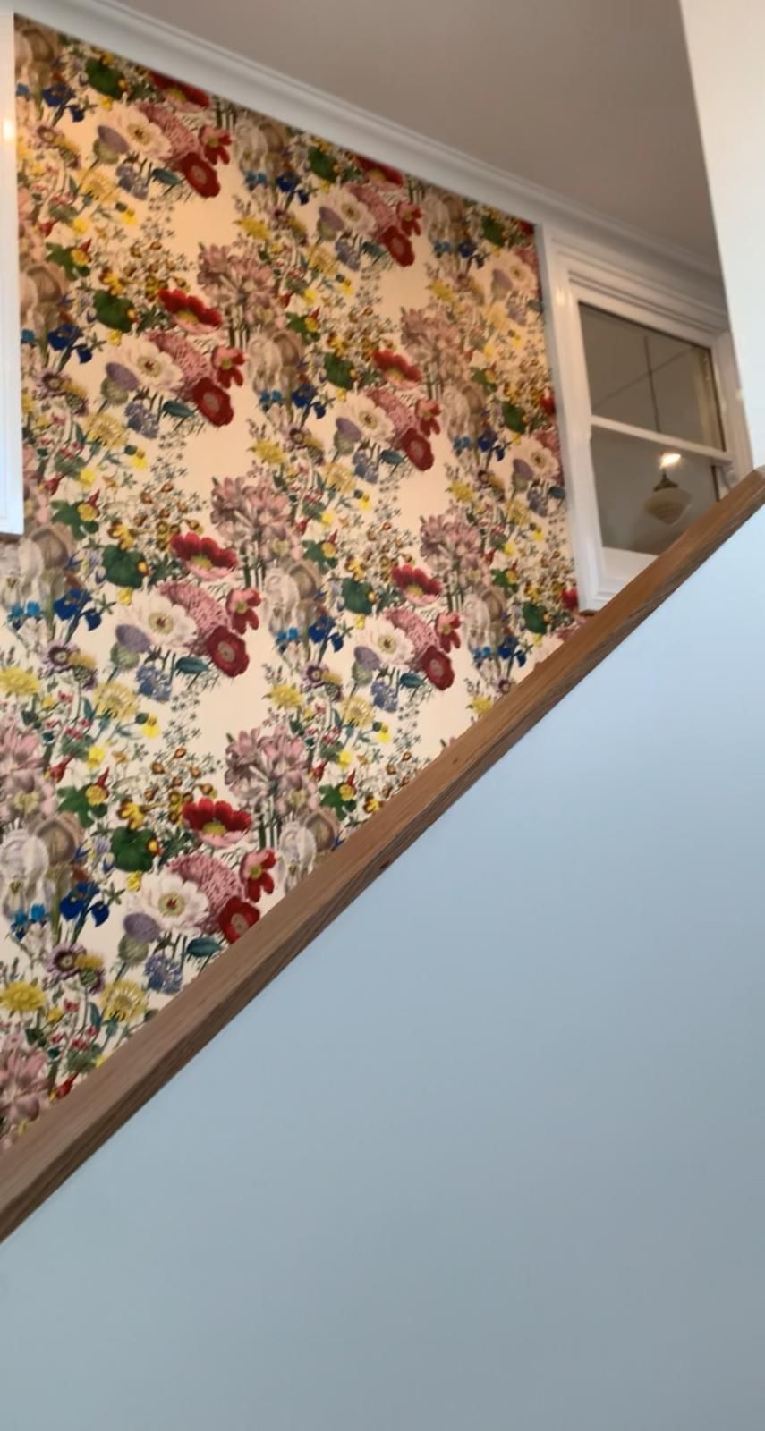 A staircase with a floral wallpaper on the wall.