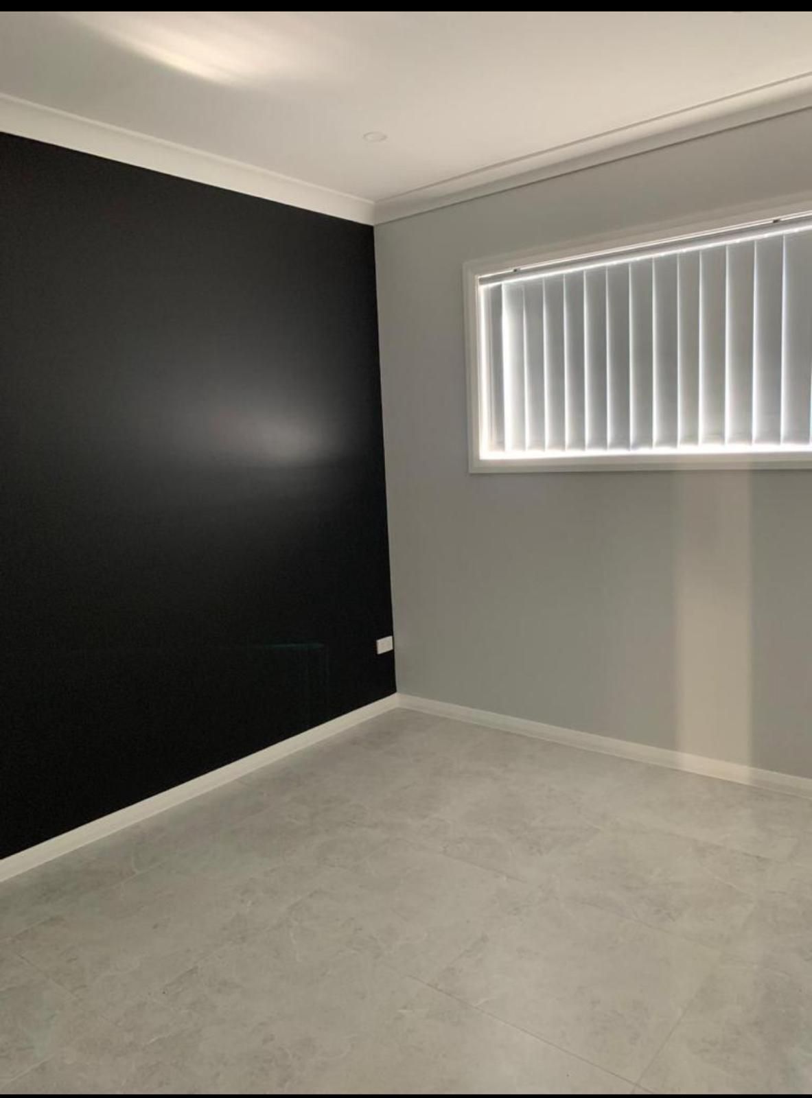 An empty room with a black wall and a window