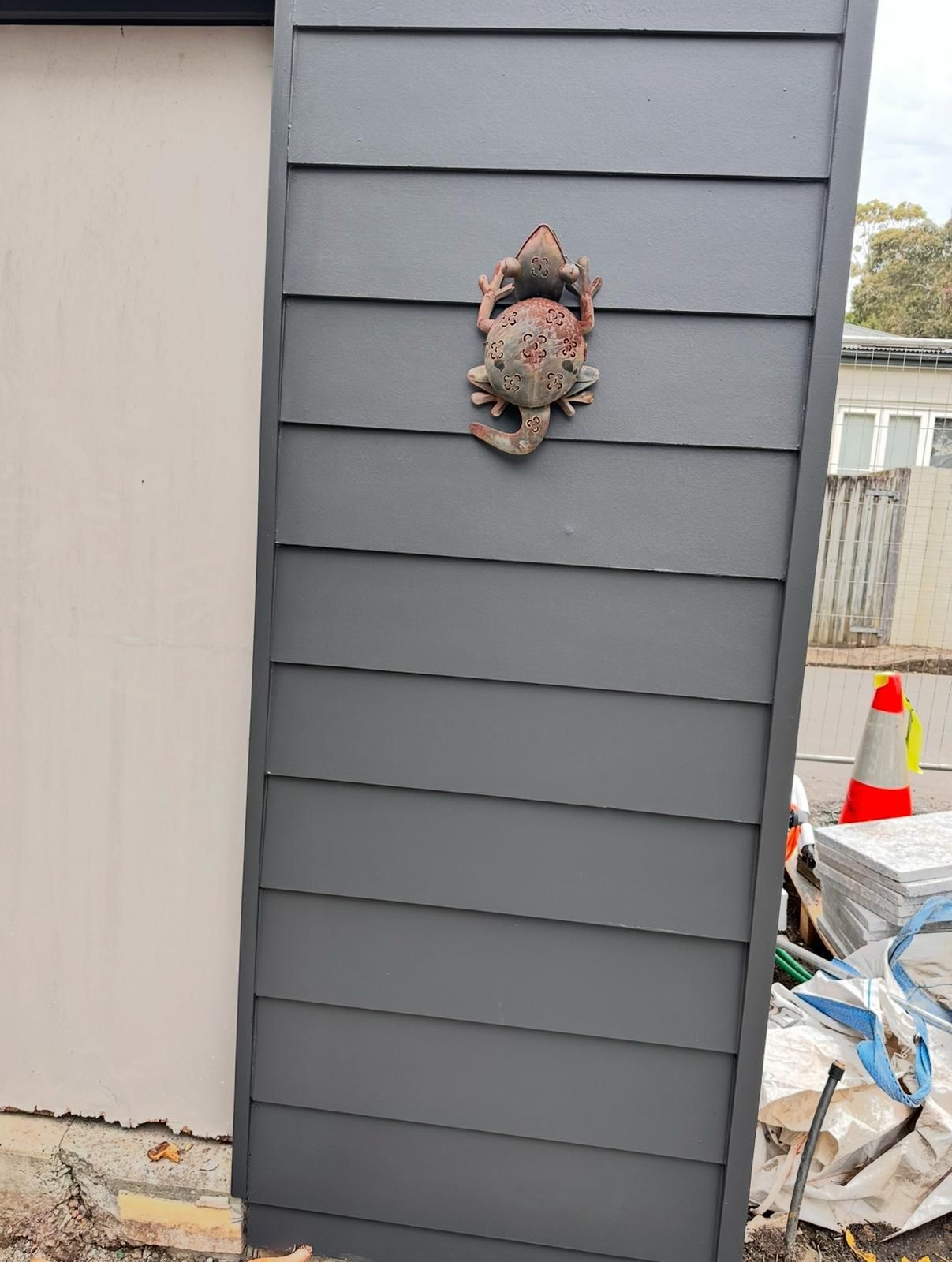 A frog is hanging on the side of a building.