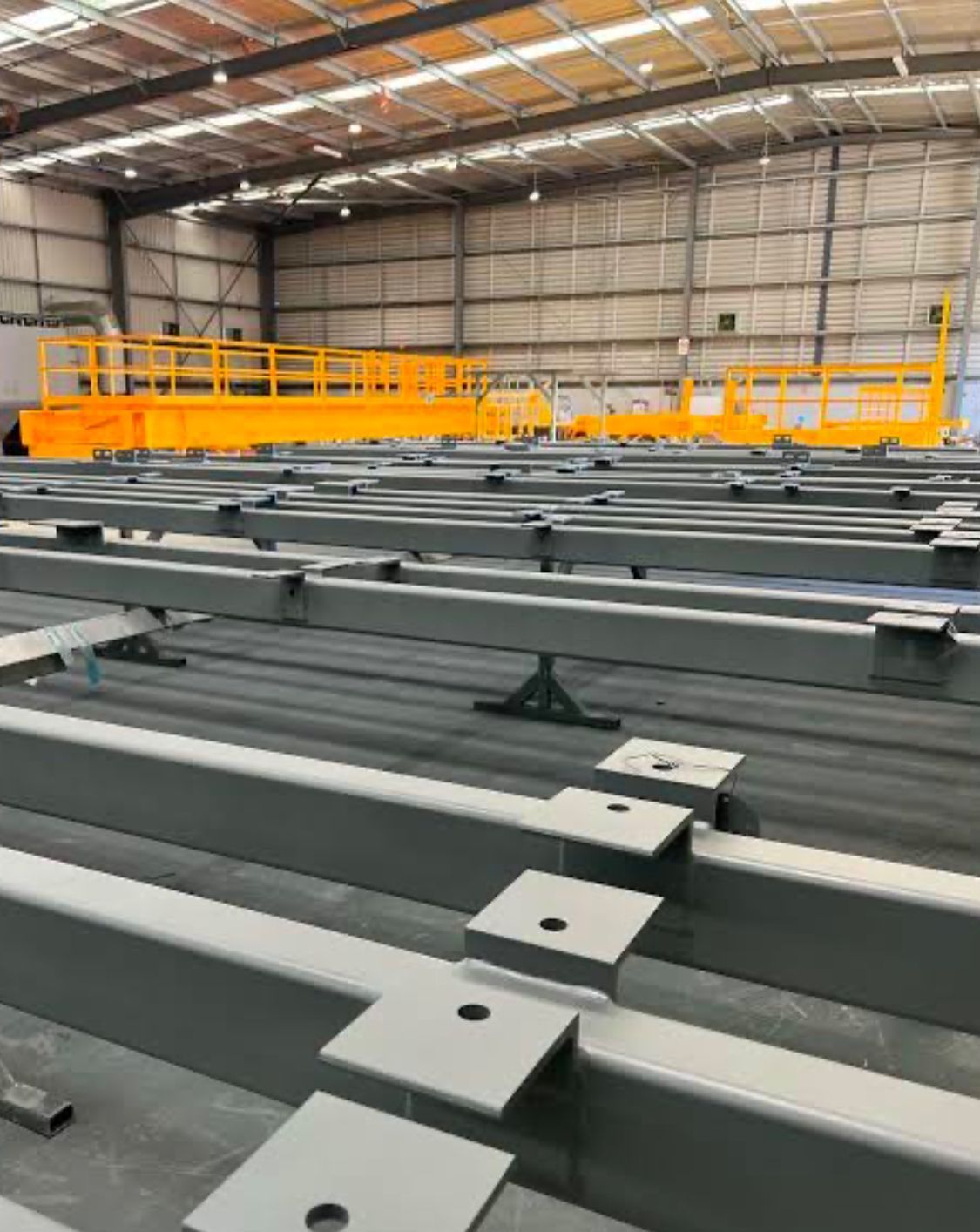 A large warehouse with a lot of metal beams and a yellow platform.