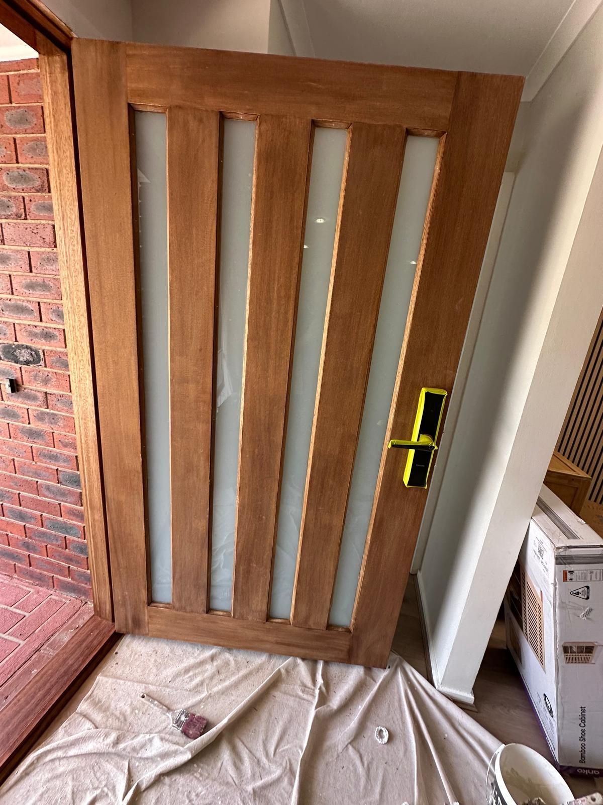 A wooden door with glass panels is being painted in a room.