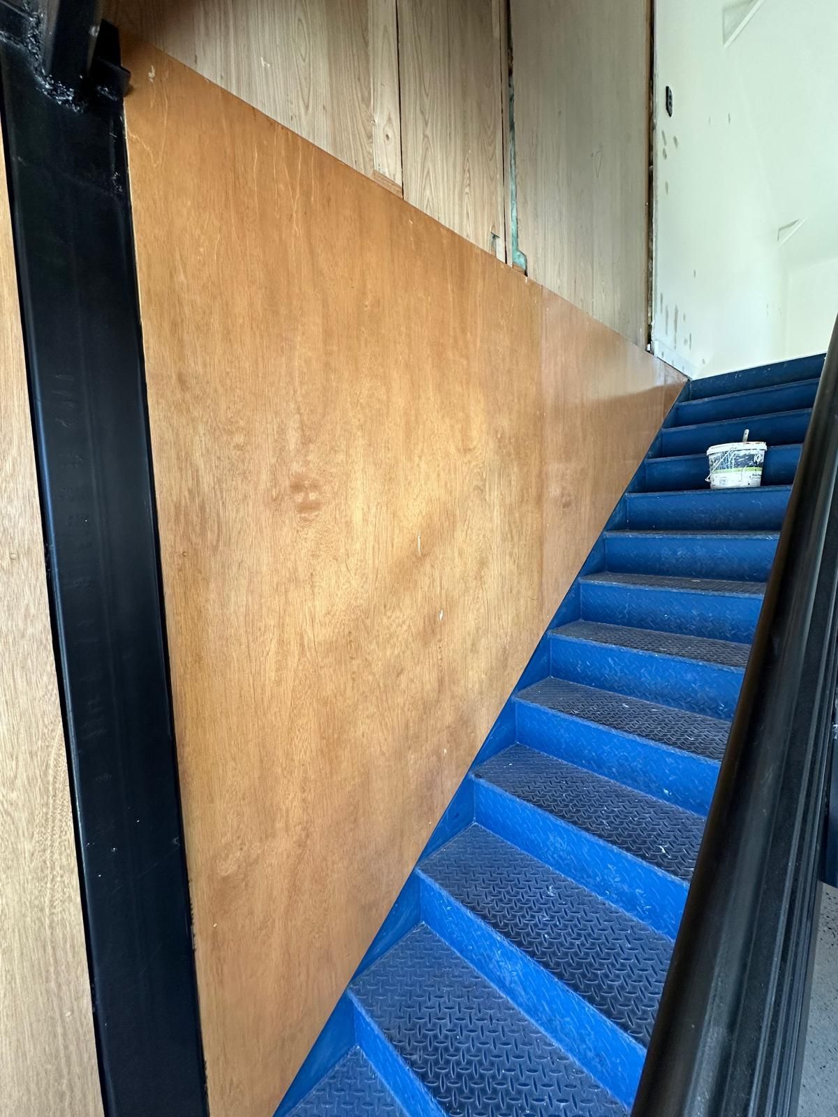 A staircase with blue steps and a wooden wall.