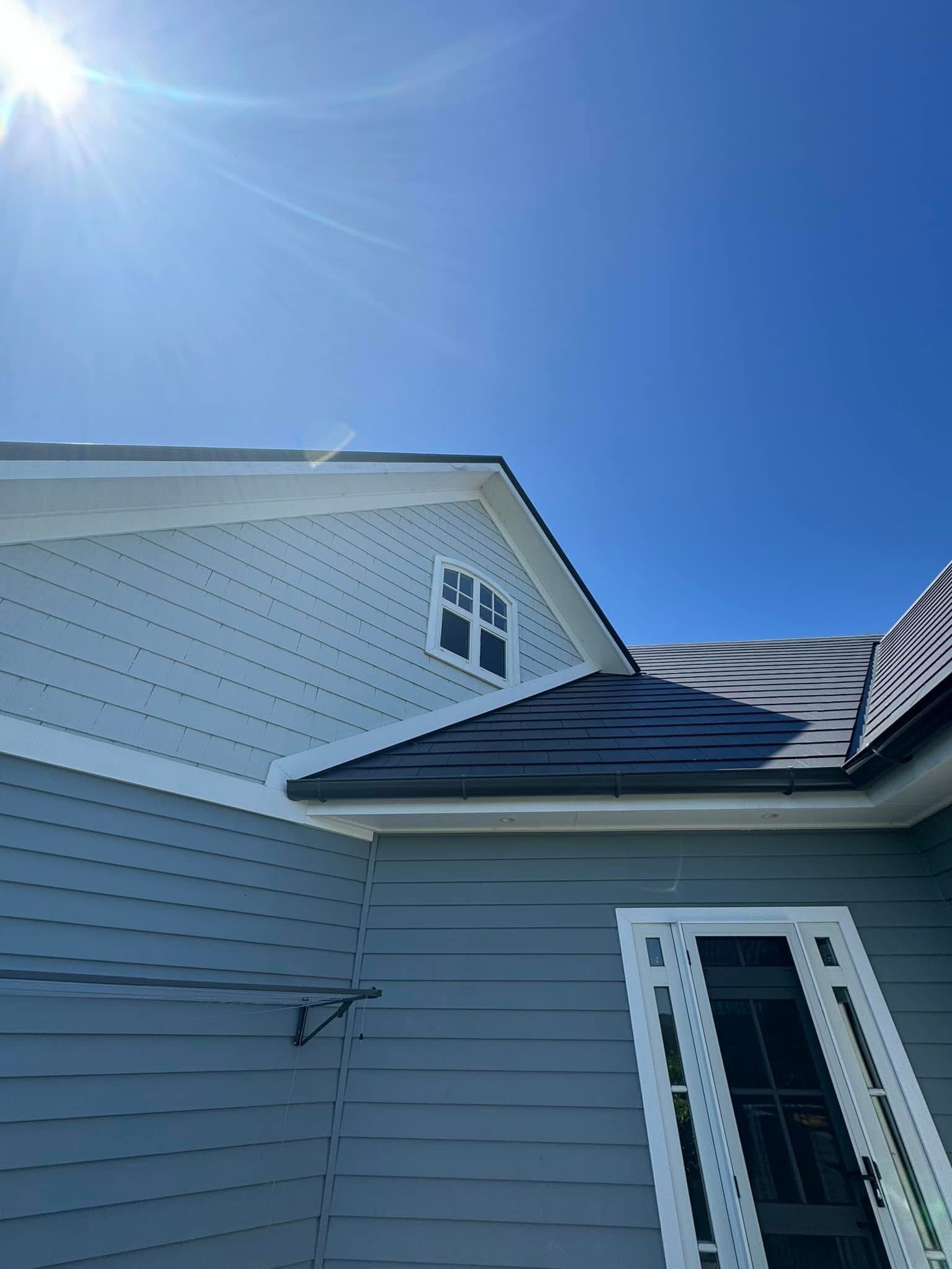 A house with a black roof and a blue sky in the background.