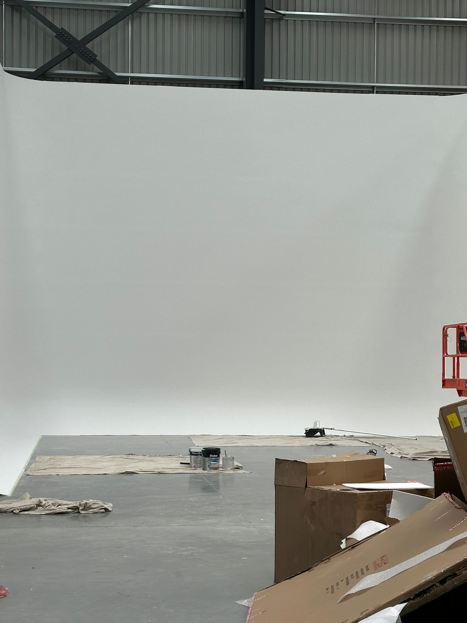A large white wall is being built in a warehouse.