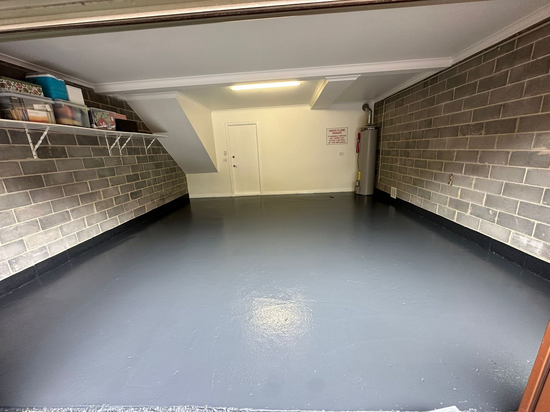 A garage with a brick wall and a gray floor.