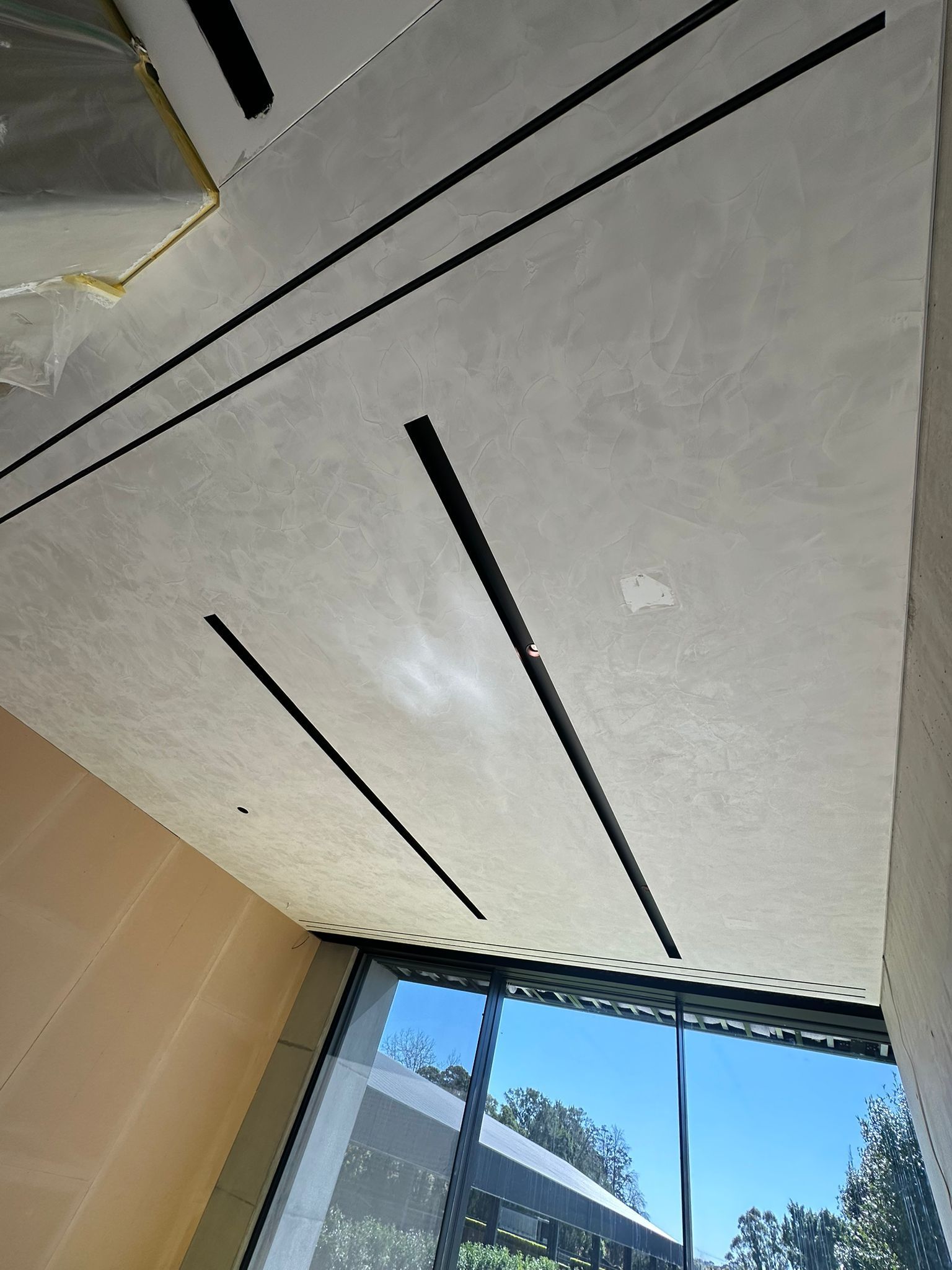 A room with a large window and a ceiling with lines on it.