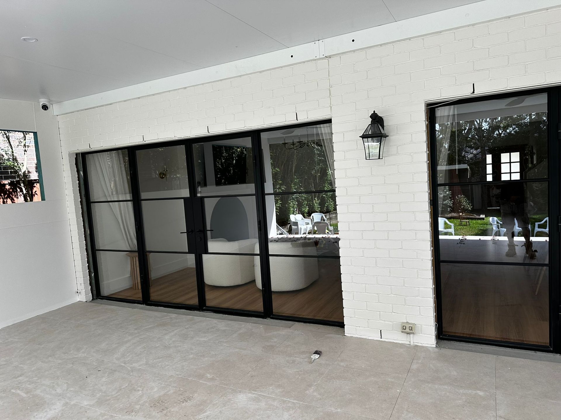 A white brick building with black windows and sliding glass doors.
