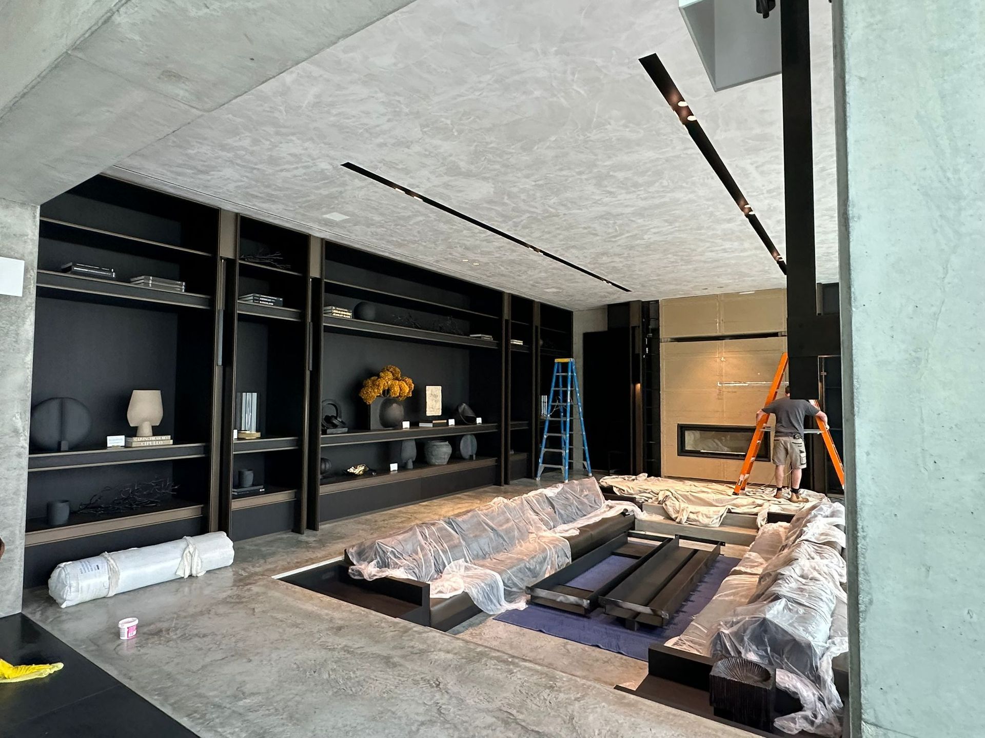 A man is standing on a ladder in a living room.