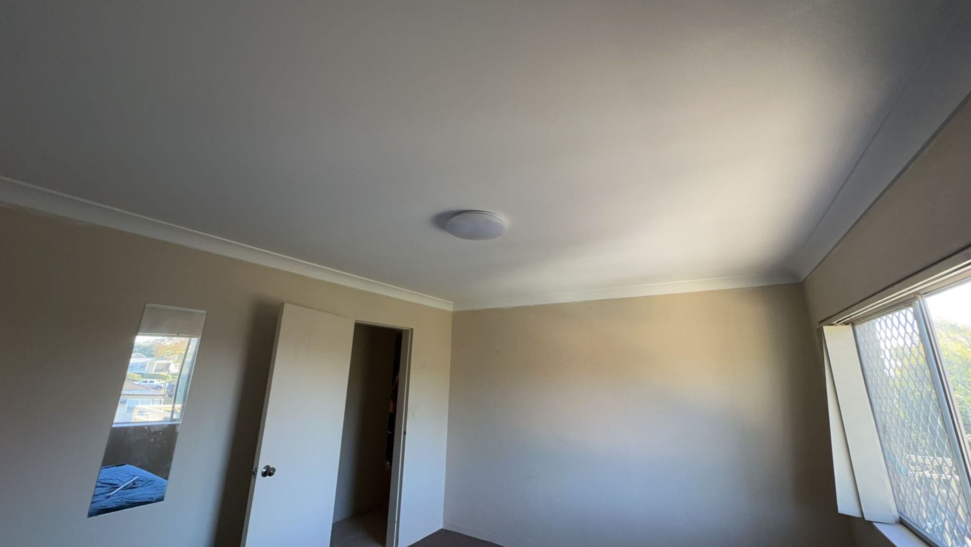 A bedroom with a ceiling light and a window.
