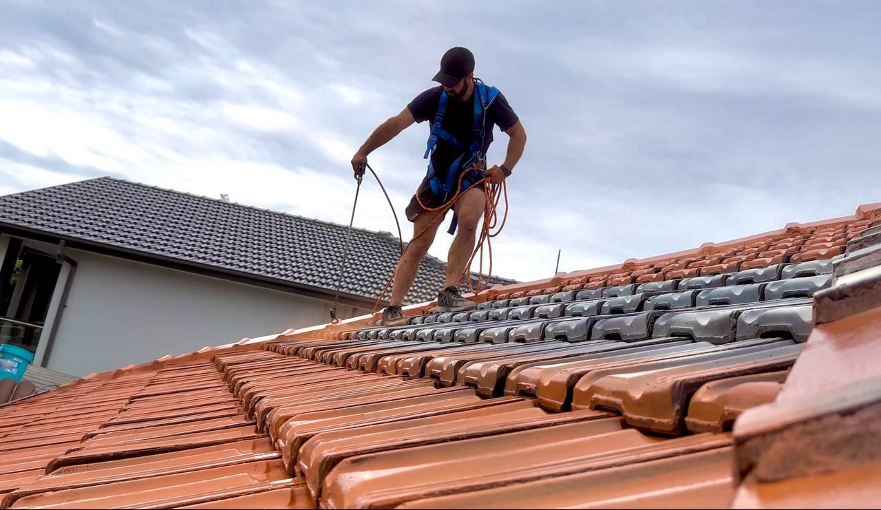 A man is standing on top of a tiled roof.