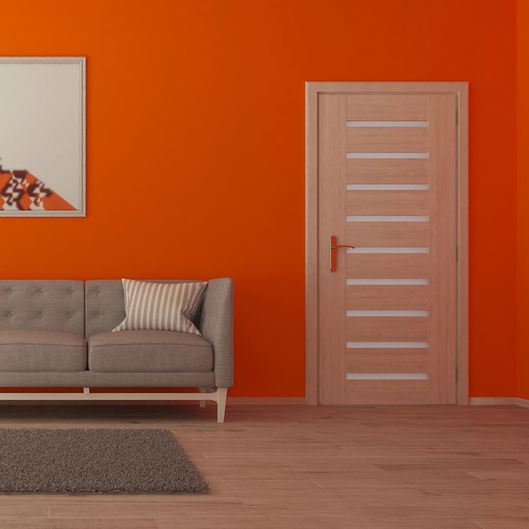 A living room with orange walls , a couch , and a door.